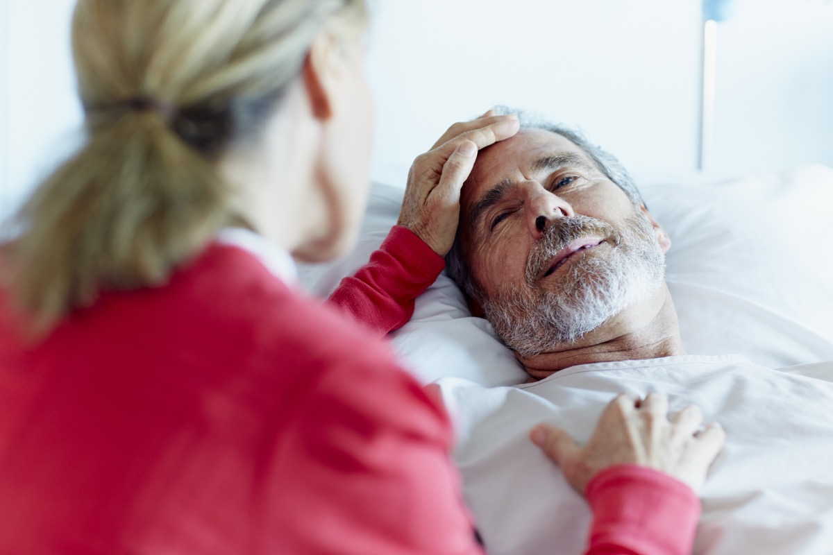 O femeie mângâie un bărbat bolnav într-o secție de spital după un atac de cord