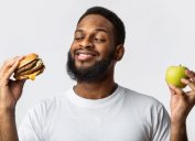 man holding a burger and an apple