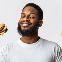 man holding a burger and an apple