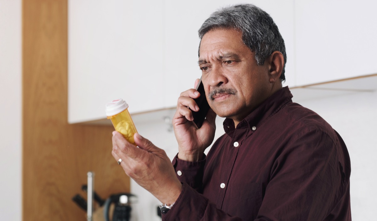 Shot of a senior man reading the label on a medicine container and talking on a cellphone