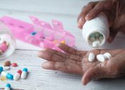 Elderly woman pouring pills from bottle on hand, closeup view