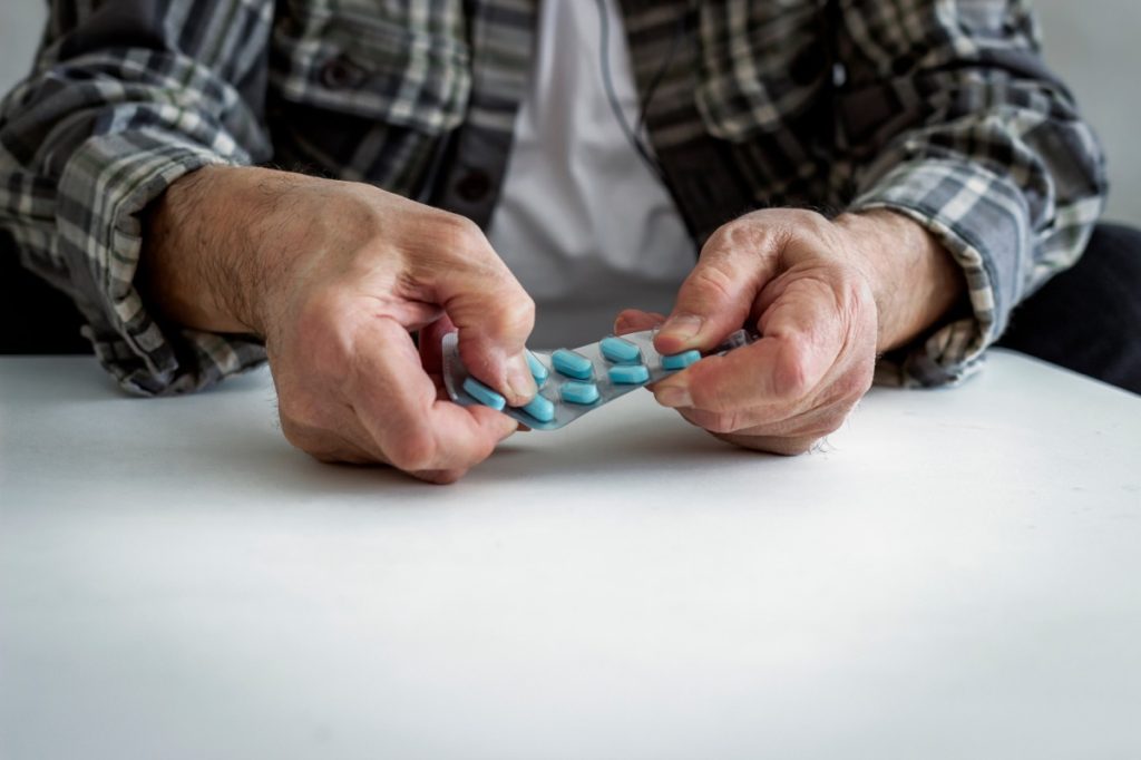 older man taking blue supplements