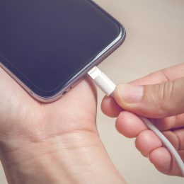 Hands plugging in an iPhone charger into its base