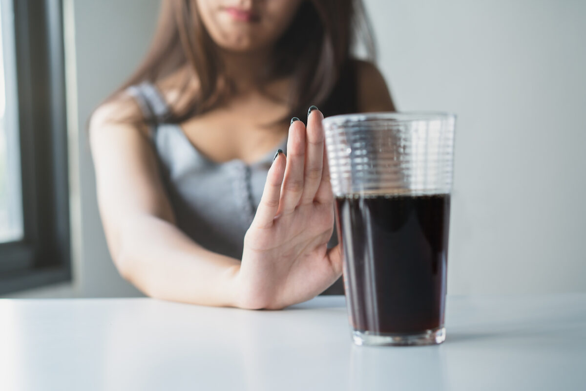 woman holding palm to diet soda, glass of diet cola