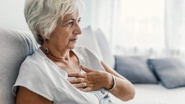 aged woman having heart attack. Woman is clutching her chest, acute pain possible heart attack. Heart disease. People with heart problem concept