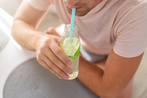 Ein Mann trinkt Zitronenwasser durch einen Strohhalm