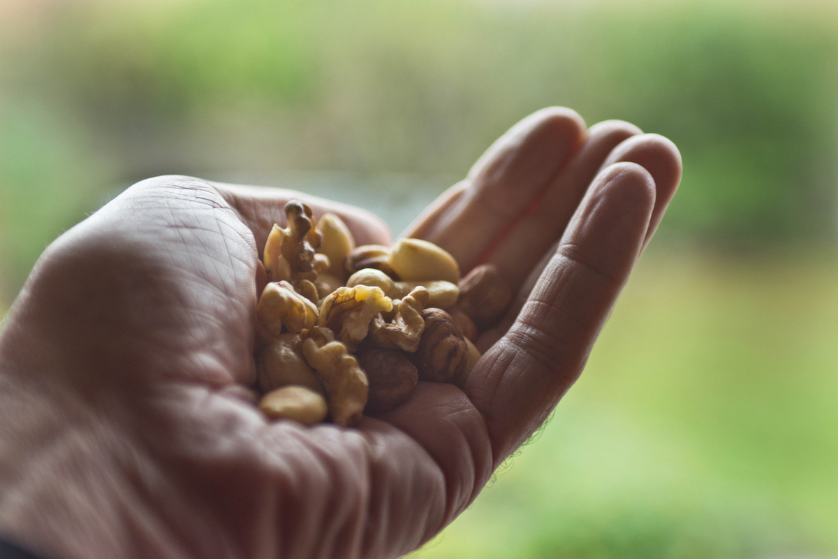 Naturalistic shot of a senior man holding a handful of nuts.