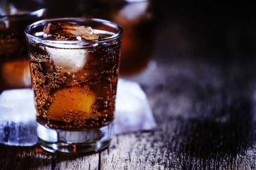 bourbon cola with whiskey and ice cubes on vintage wooden background