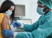 woman getting vaccine from doctor in face shield and scrubs
