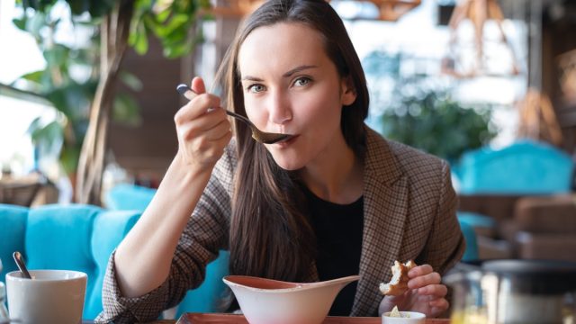 brunette woman eating soup in restaurant