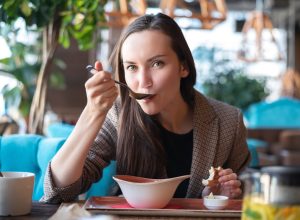 brunette woman eating soup in restaurant