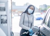 A young woman wearing a face mask and gloves fills her car's gas tank.