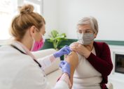 A senior woman receiving a COVID-19 vaccination from a female healthcare worker