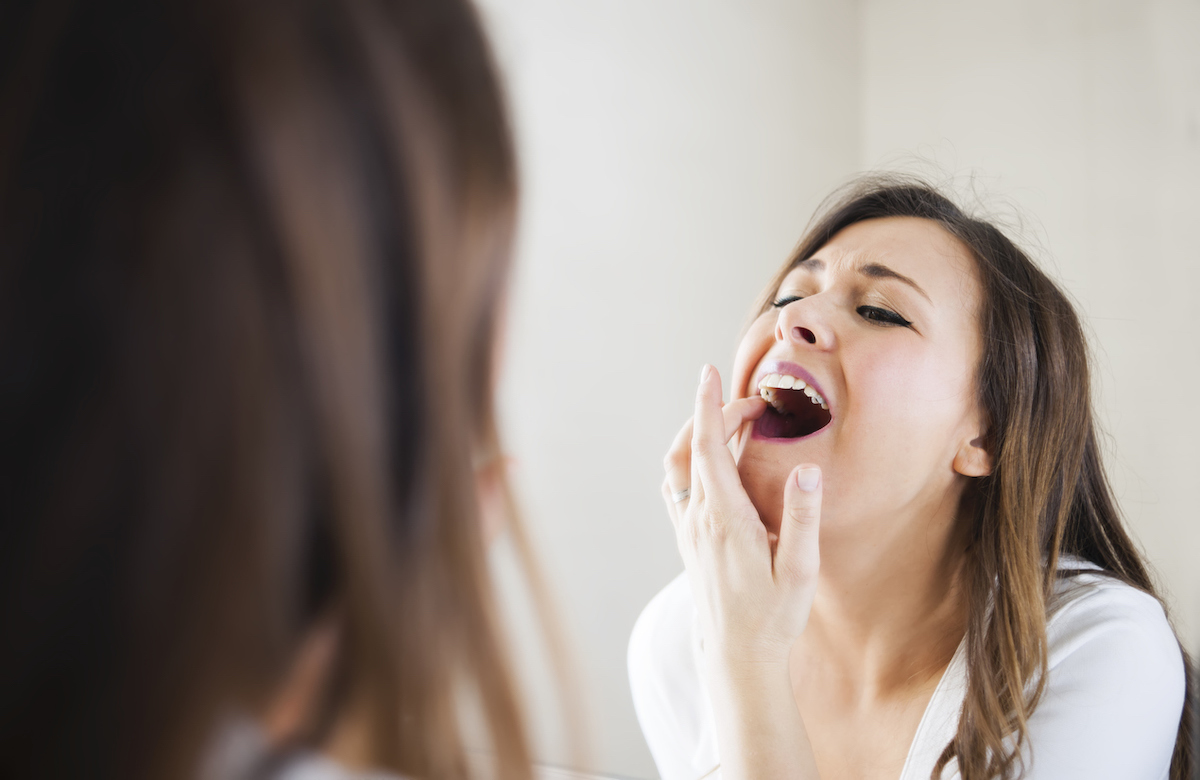 Woman looking her self in mirror, she has toothache