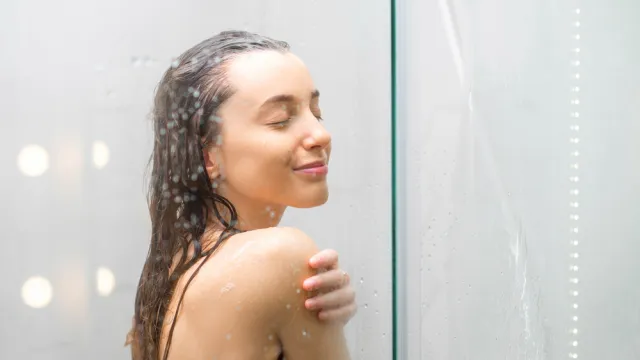 A young woman stands smiling in the shower