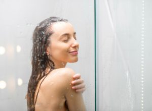 A young woman stands smiling in the shower