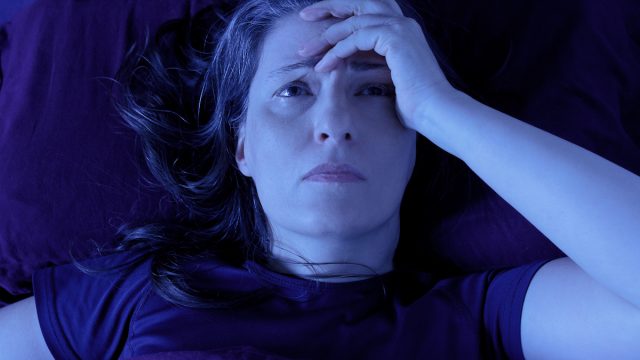 Middle aged woman lying awake in her bed at night