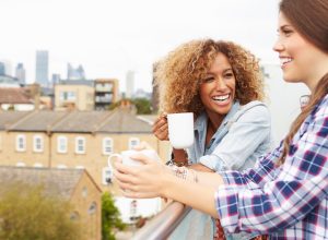 two women drinking coffee on rooftop
