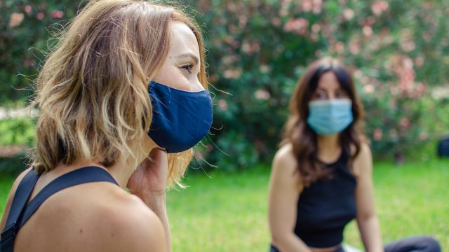 Two friends talking in the park with face masks