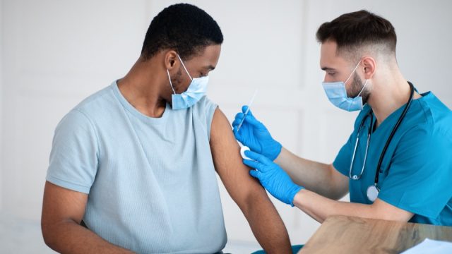 doctor giving young man a covid vaccine