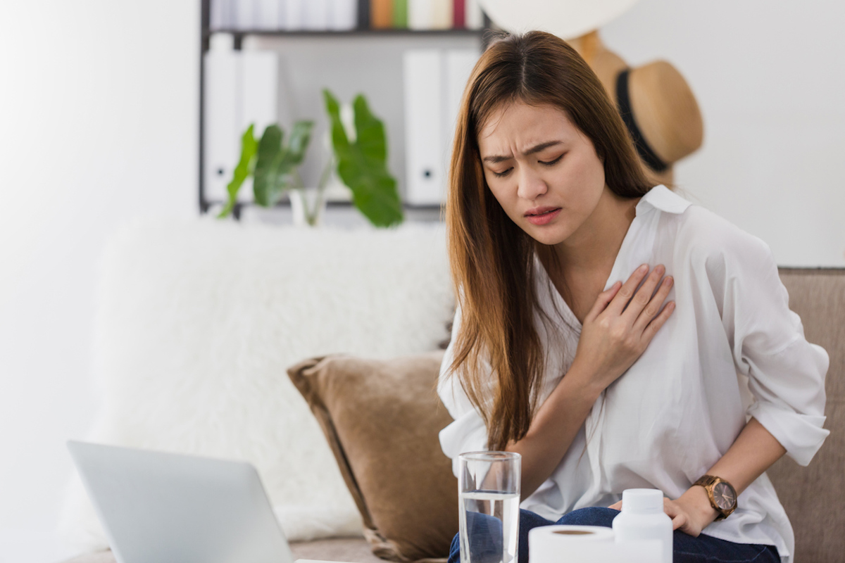 Woman sick, feeling pain in the chest while working with a laptop.