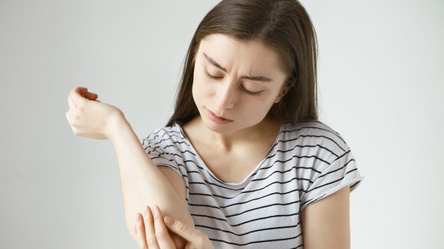young woman studying skin on her arm