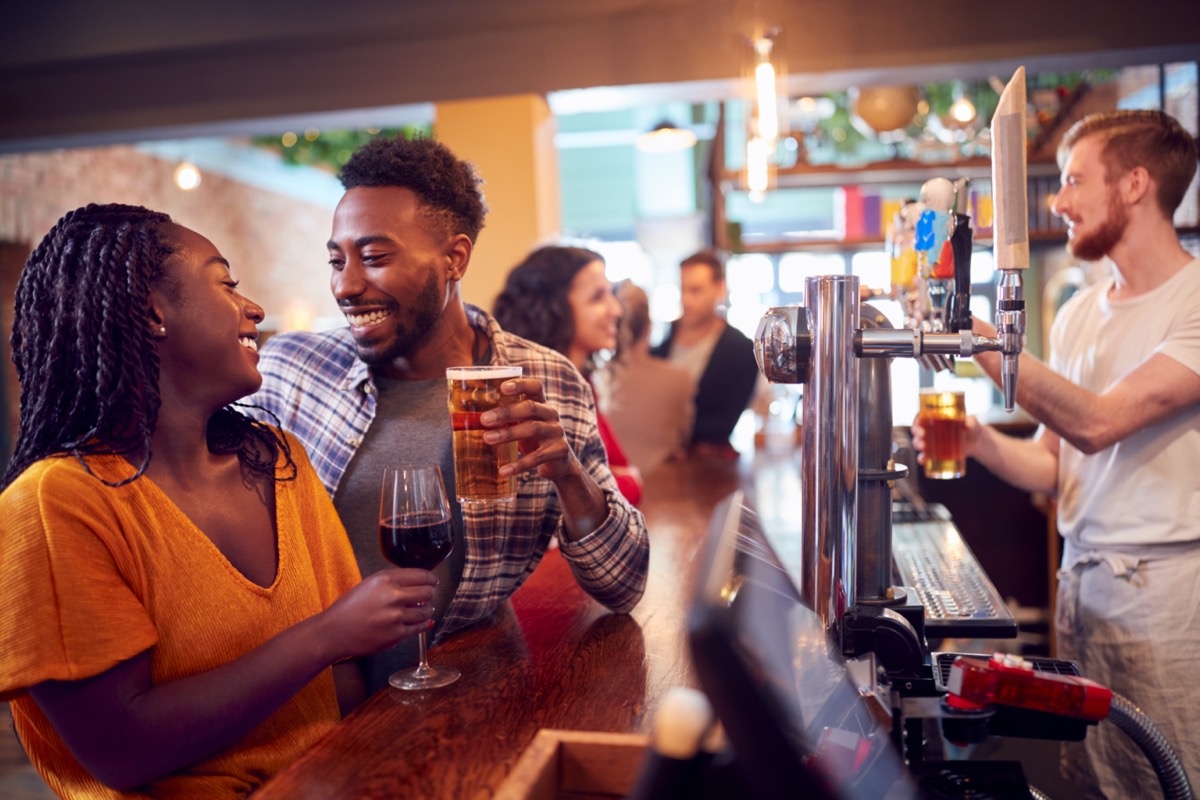 Young man and woman drinking beer and hitting it off at a bar