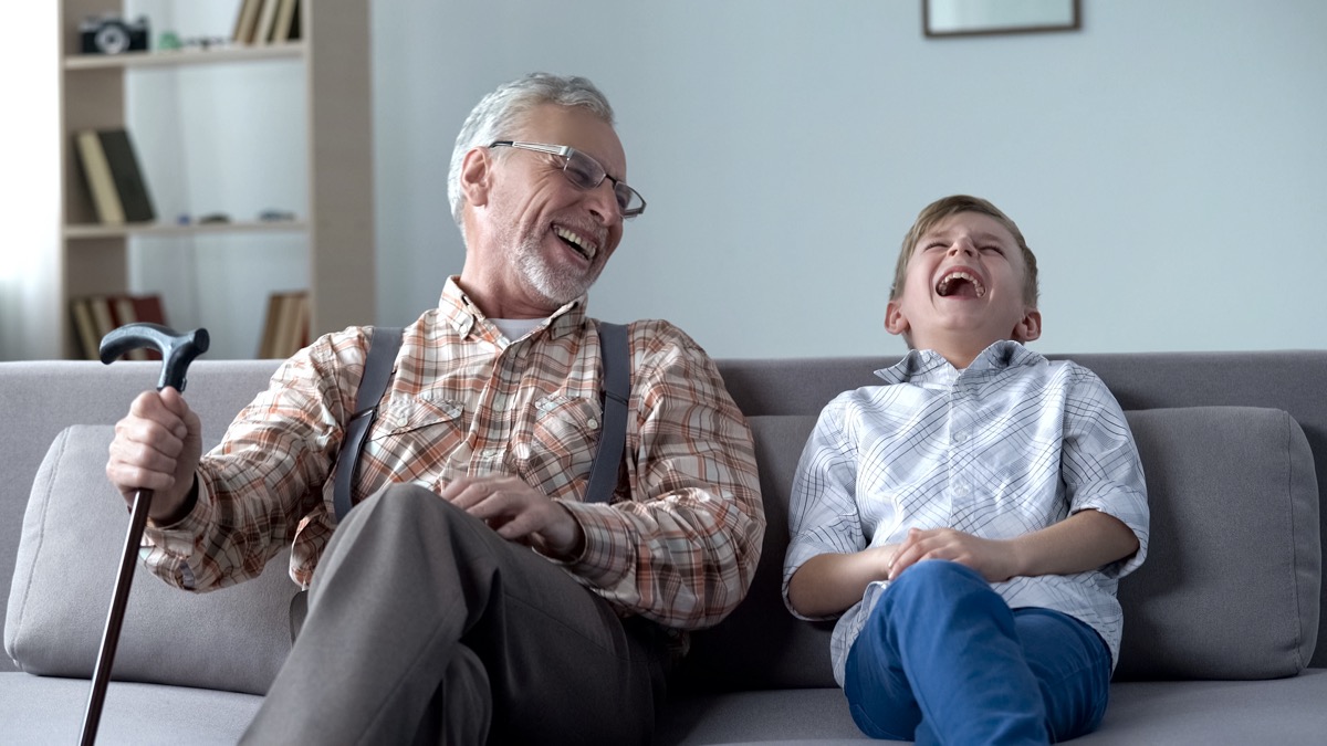 Senior man and young boy laughing on couch