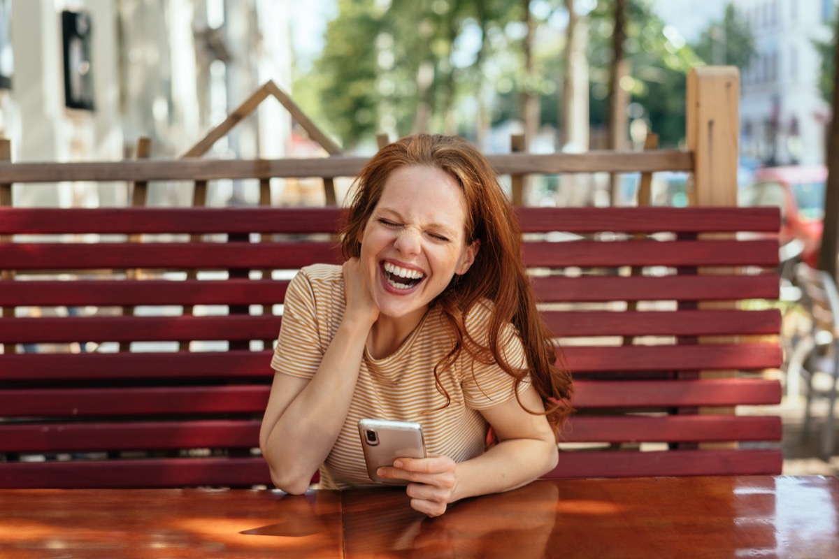 Young woman holding phone and laughing