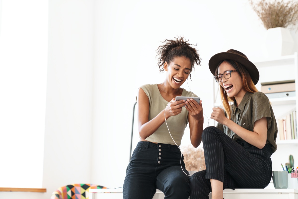 Two young women looking at phone laughing