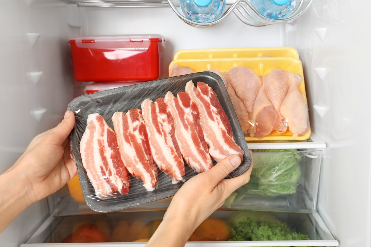 person taking styrofoam tray of bacon out of the fridge