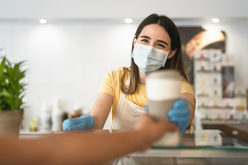 A barista handing a coffee to a customer