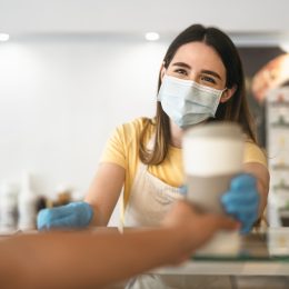 A barista handing a coffee to a customer