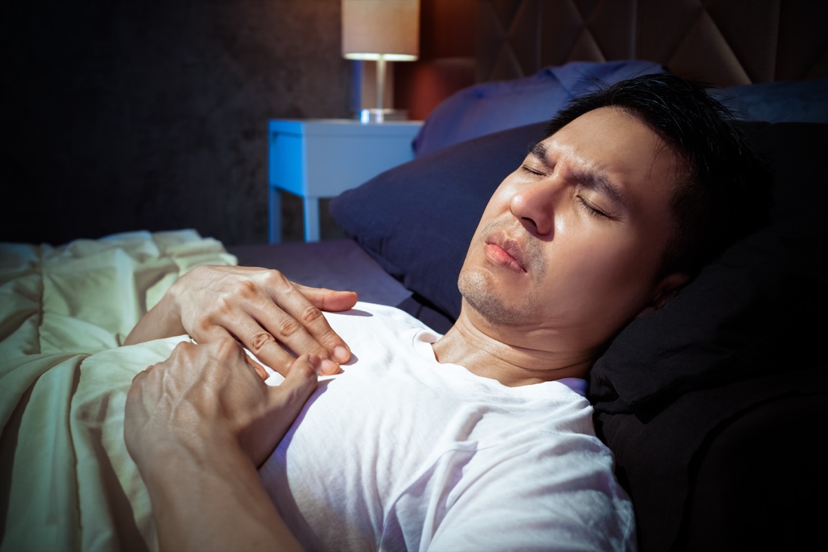 man has a heart attack symptoms while sleeping on bed at night