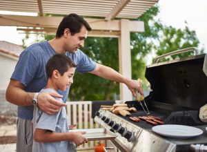 father teaching son how to grill hot dogs and bonding