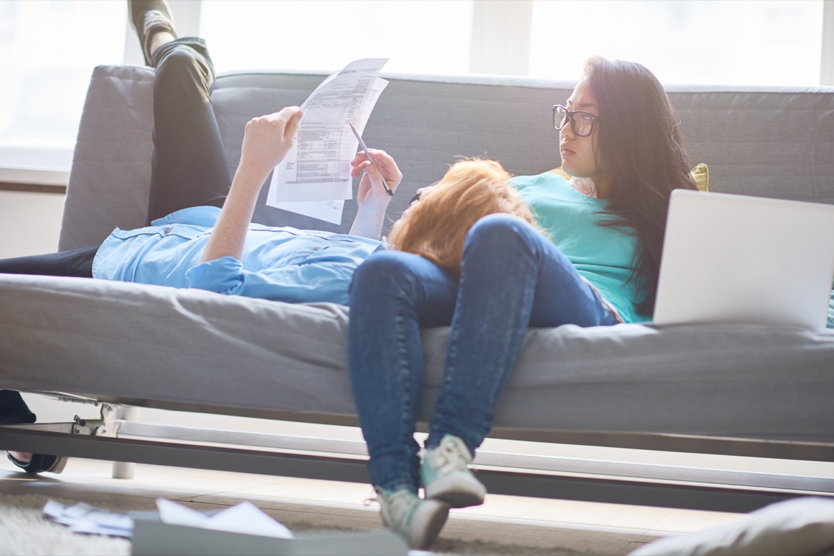  couple examining tax papers and relaxing on sofa at home