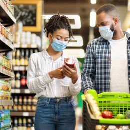 A young couple shopping for groceries with a cart