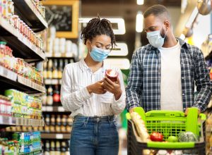 A young couple shopping for groceries with a cart