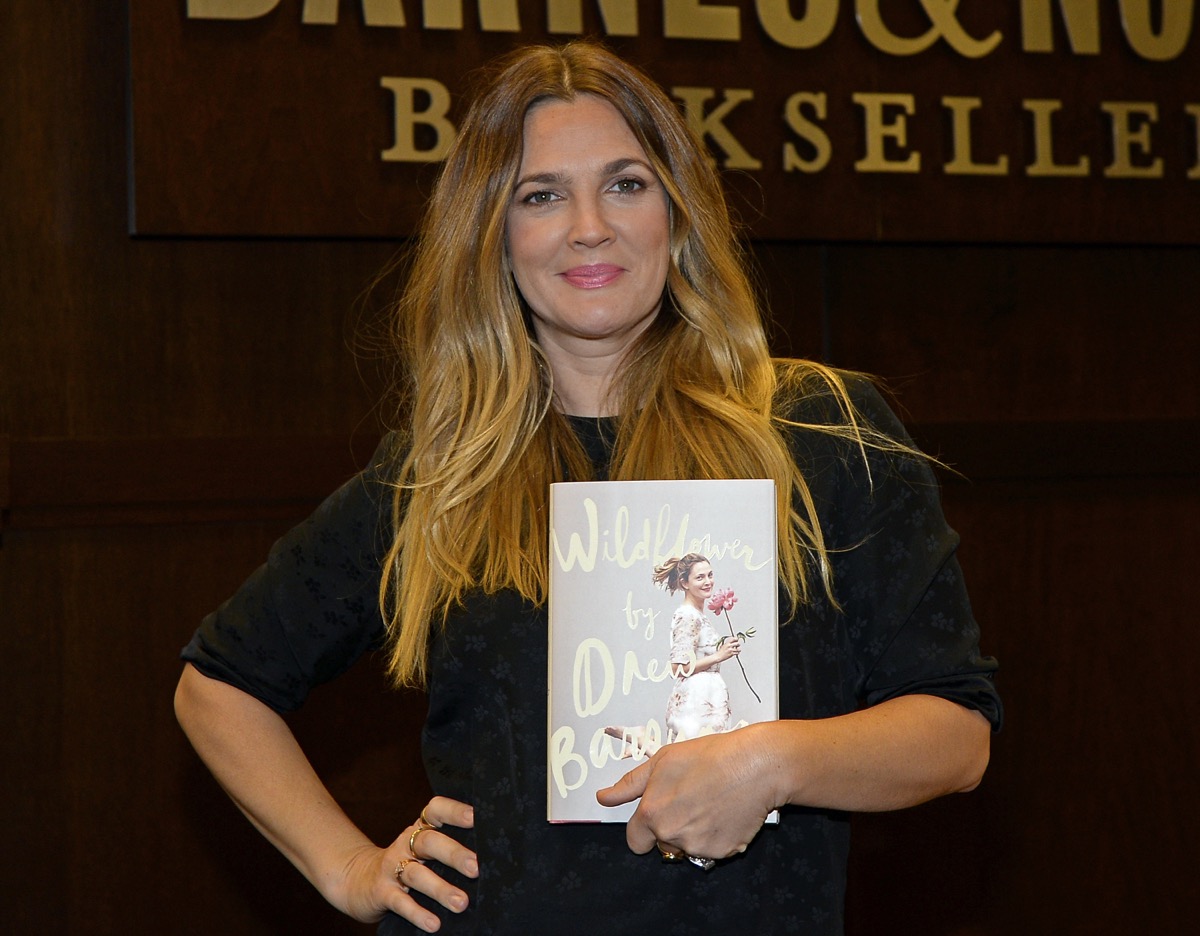 drew barrymore holding copy of her book, wildflower, in front of barnes and noble sign