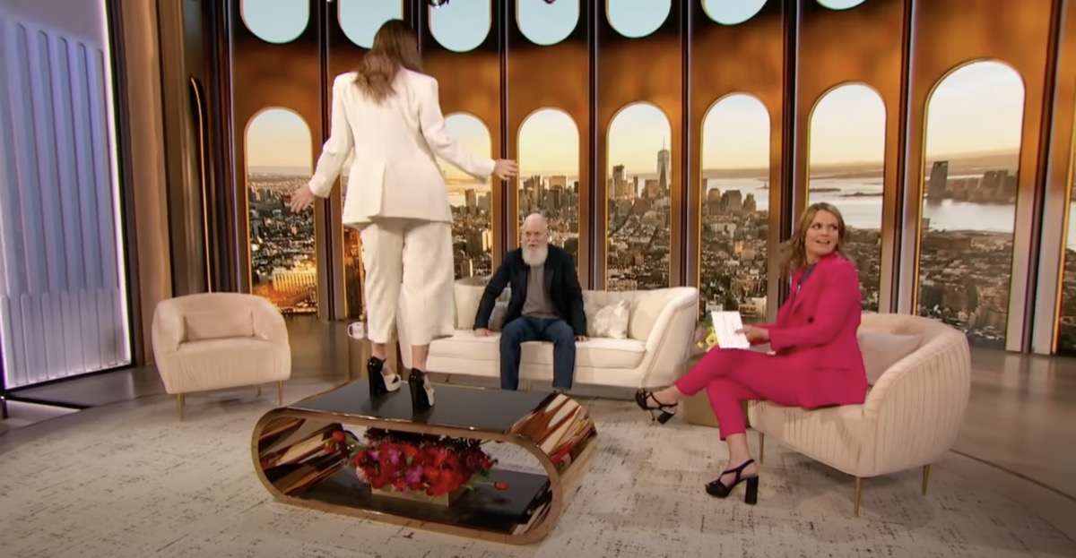 drew barrymore standing on table while david letterman and savannah guthrie look on