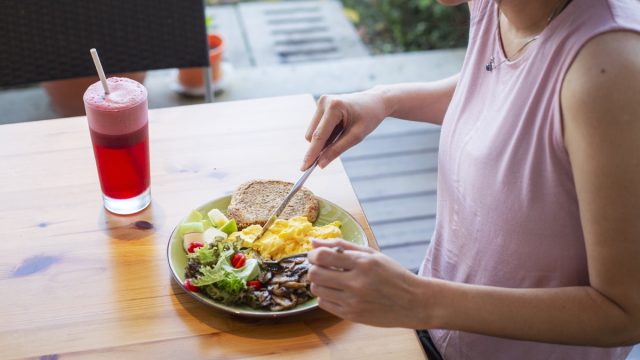 unrecognized woman eating healthy homemade breakfast with salad at backyard garden