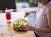 unrecognized woman eating healthy homemade breakfast with salad at backyard garden