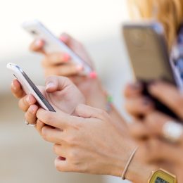 A shot of three people holding smartphones outdoors.