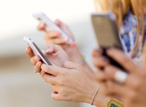 A shot of three people holding smartphones outdoors.