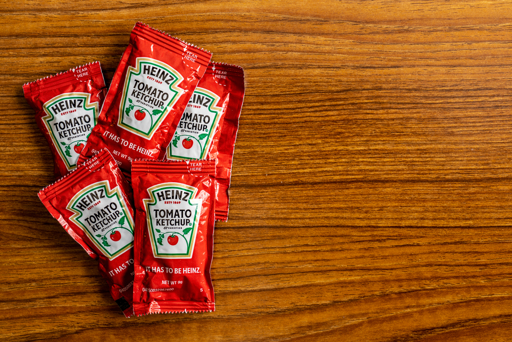 Five packets of Heinz tomato ketchup sitting on a tabletop