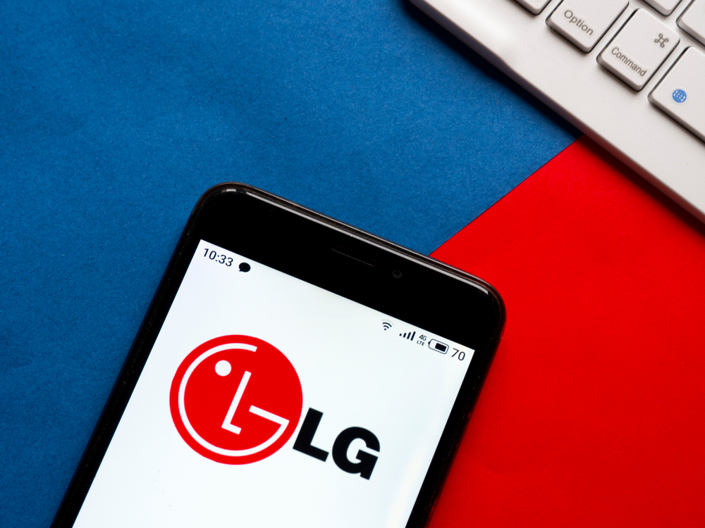 An LG smartphone with the company's logo on the screen resting near a computer keyboard