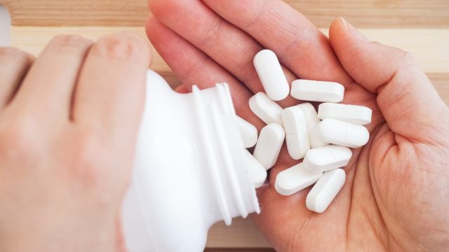 Woman taking magnesium pills out of a bottle. Close up.