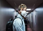 Shot of a young man wearing a mask while boarding a plane