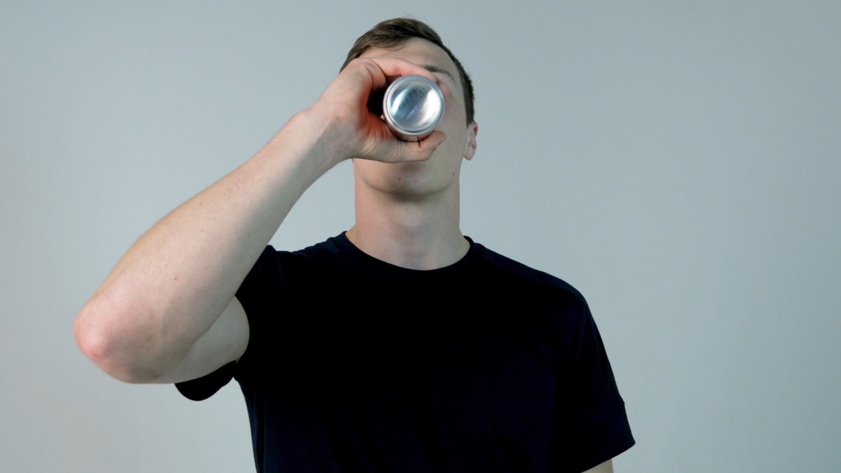Young man drinking soda. Young man in black shirt drinking soda, on a white background