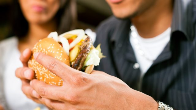 man eating burger while woman watches
